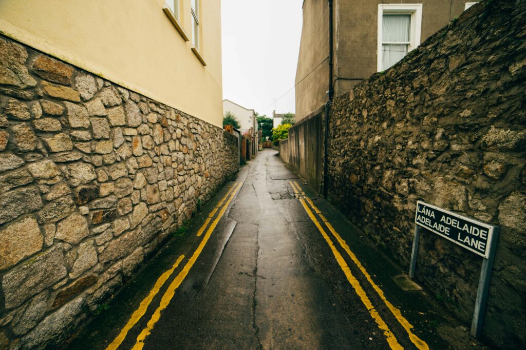 A narrow deserted alleyway in Dublin, with wet stone walls and a street sign.